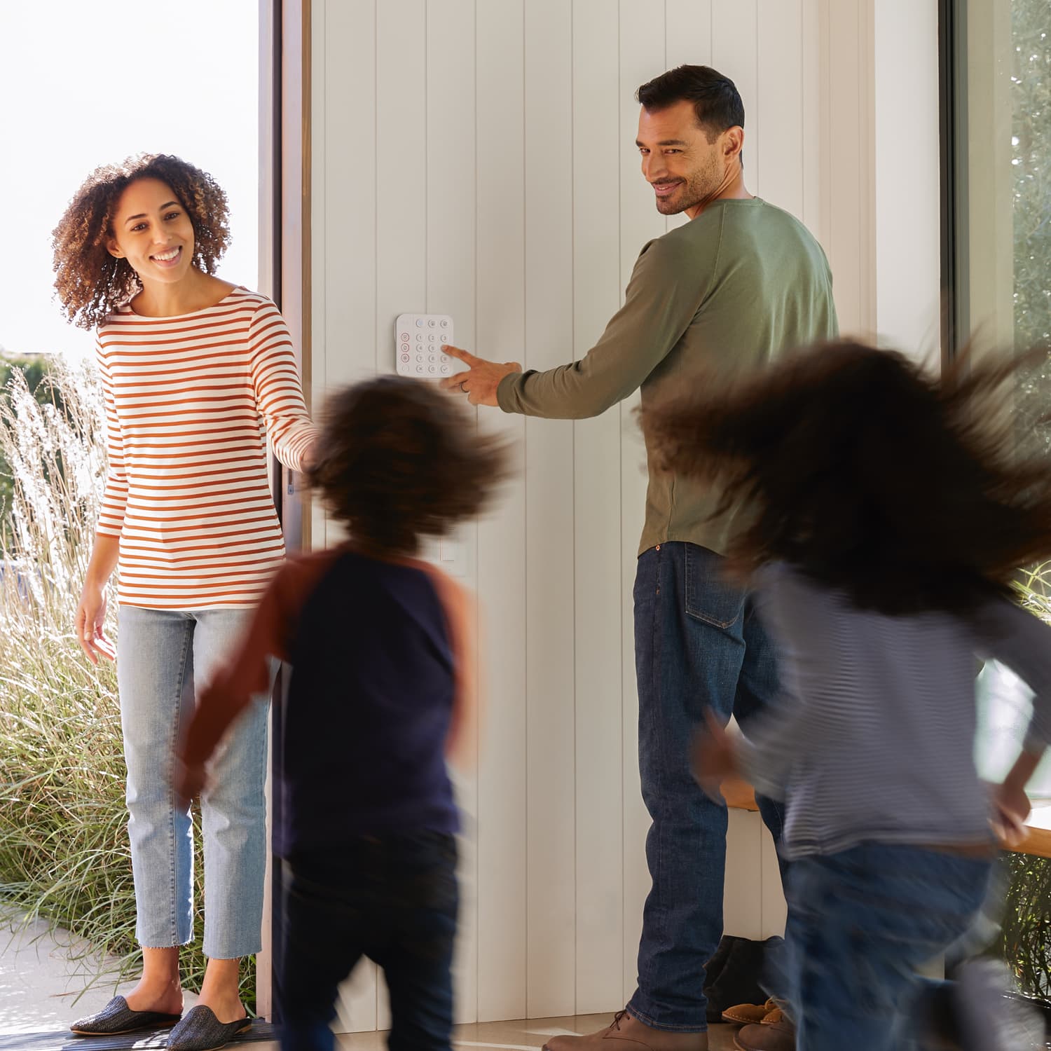 Alarm Security Kit, 5-Piece (for 2nd Generation) - Family exiting home as man uses a Ring Alarm Keypad on the wall, with two kids running toward a woman in doorway.