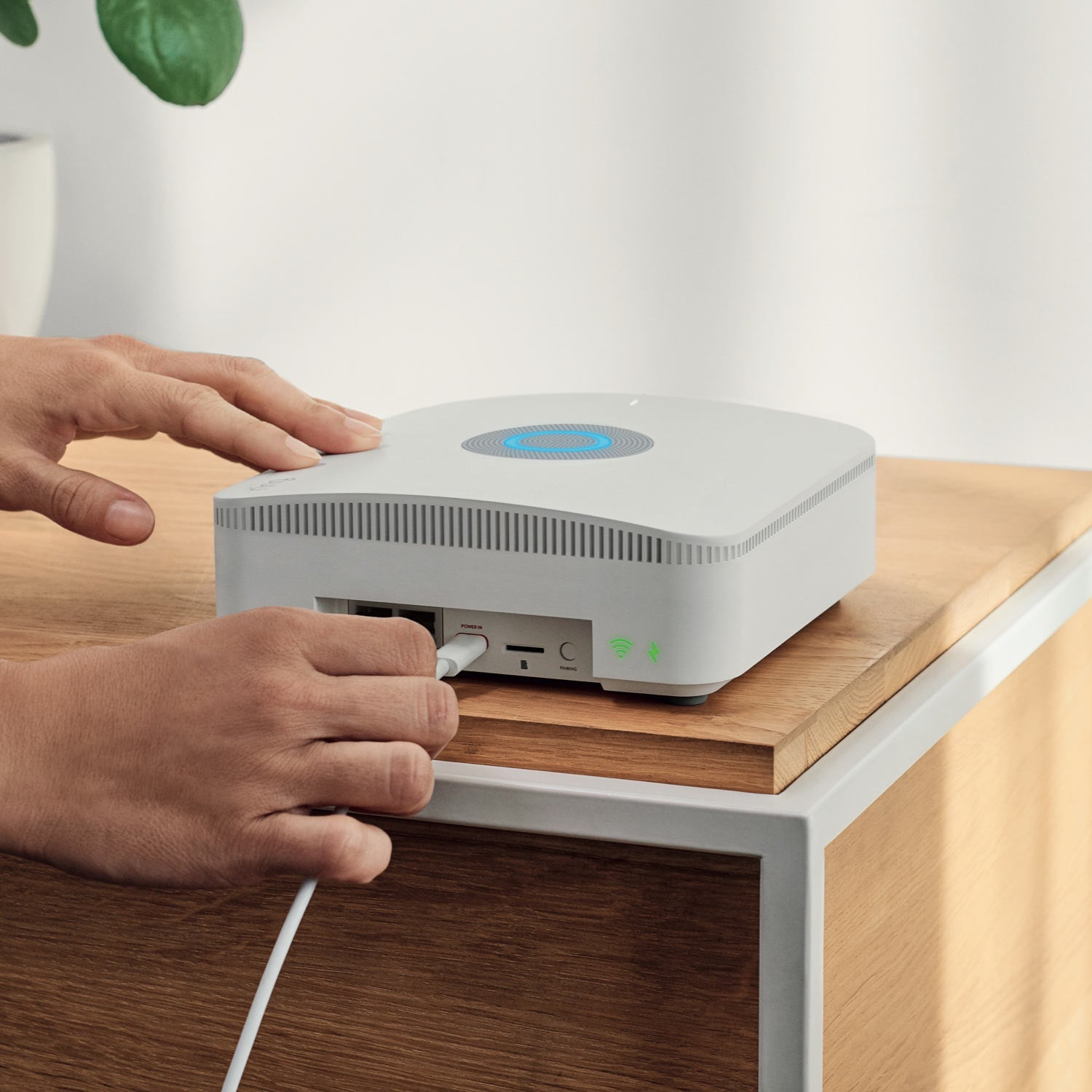 Alarm Pro, 13-Piece Kit (with built-in eero Wi-Fi 6 router and additional eero 6 Wi-Fi Router) - Person plugging power cord into Ring Alarm Pro Base Station, with blue light glowing on top and ports visible.