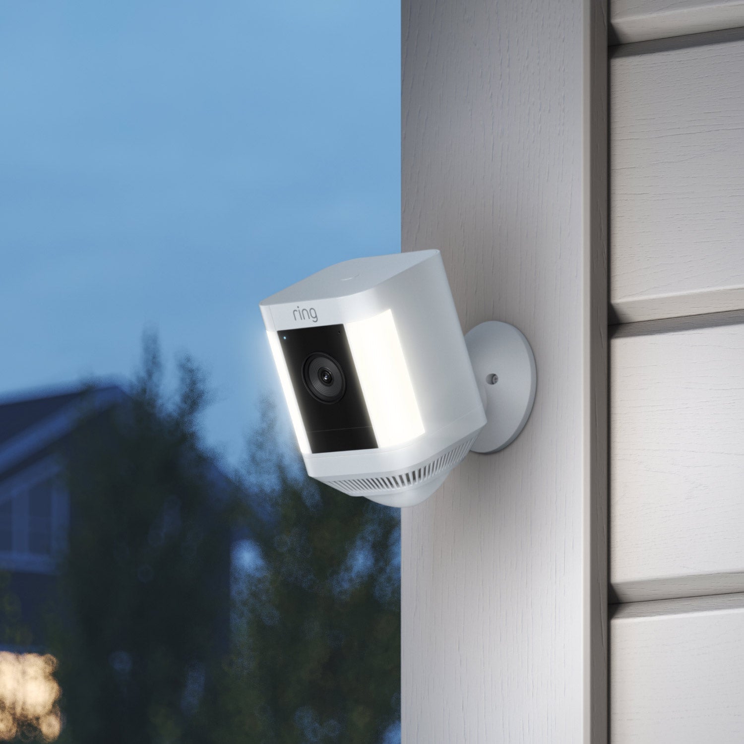 Spotlight Cam Plus - Battery:White Ring Spotlight Cam Plus with motion-activated lights and camera, on exterior wall at dusk.