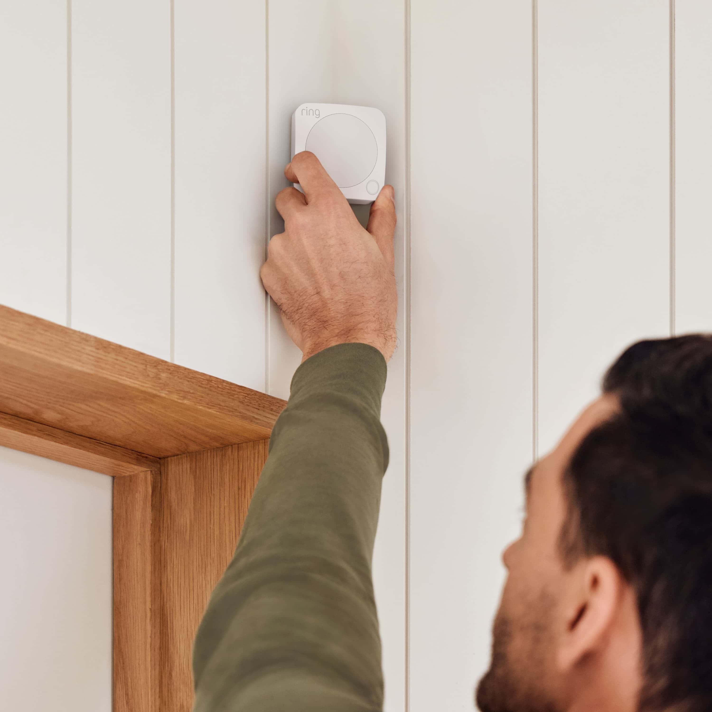 Alarm Security Kit, 8-Piece (Certified Refurbished) - Man installing Ring Alarm Motion Detector above a doorway, showing easy setup of Ring Alarm Security Kit components.