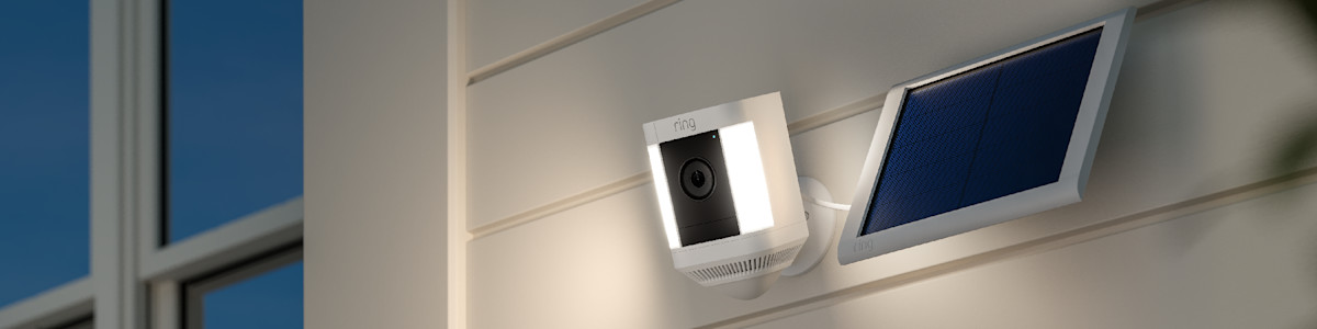 A white Ring security camera attached to a solar panel mounted on the wall