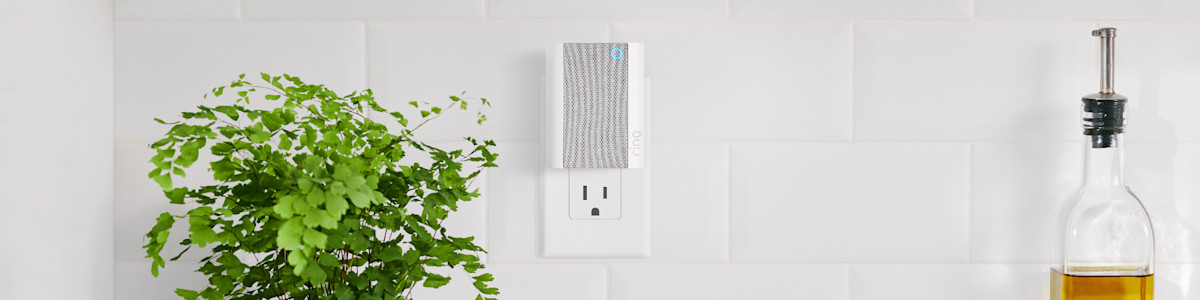 A white and grey Chime mounted on a white wall near wooden kitchen utensils