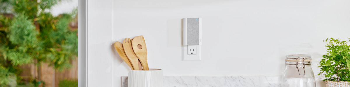 A white and grey Chime Pro mounted on a white wall near wooden kitchen utensils