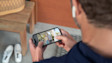 Hands holding a smartphone displaying a couple in front of a house
