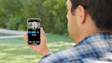 Person using smartphone app outdoors with blurred nature background