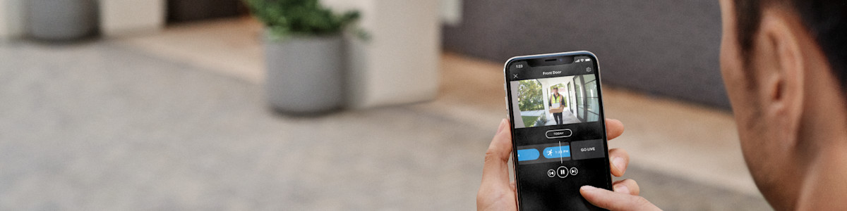 Hand holding smartphone displaying doorbell camera video feed