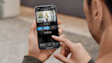 Hand holding smartphone displaying doorbell camera video feed